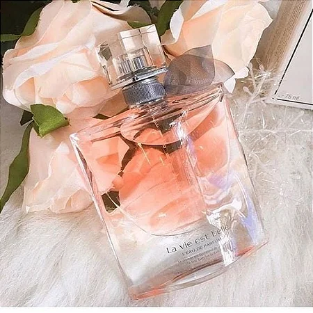 Frasco do perfume Lancôme La Vie Est Belle sobre fundo claro com flores delicadas, iluminado suavemente para destacar seu design elegante e feminino.