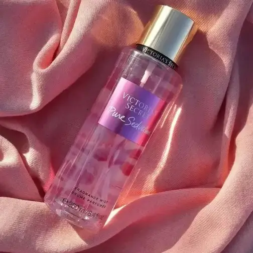 Frasco vermelho do body splash Victoria’s Secret Pure Seduction em fundo iluminado.