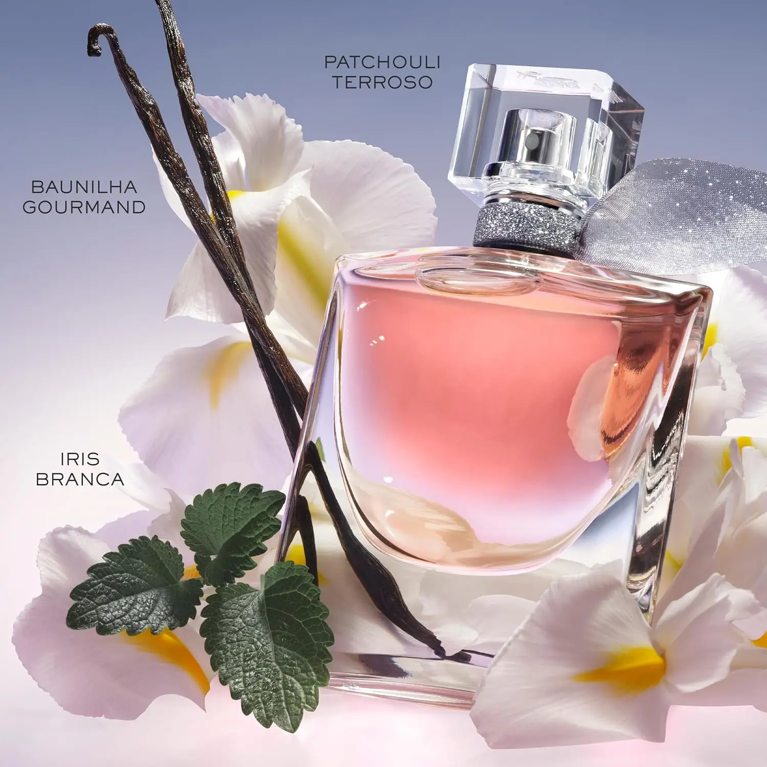 Frasco do perfume Lancome La Vie Est Belle sobre fundo lilás suave, cercado por flores de íris branca, favas de baunilha gourmand e folhas verdes que representam o patchouli terroso.