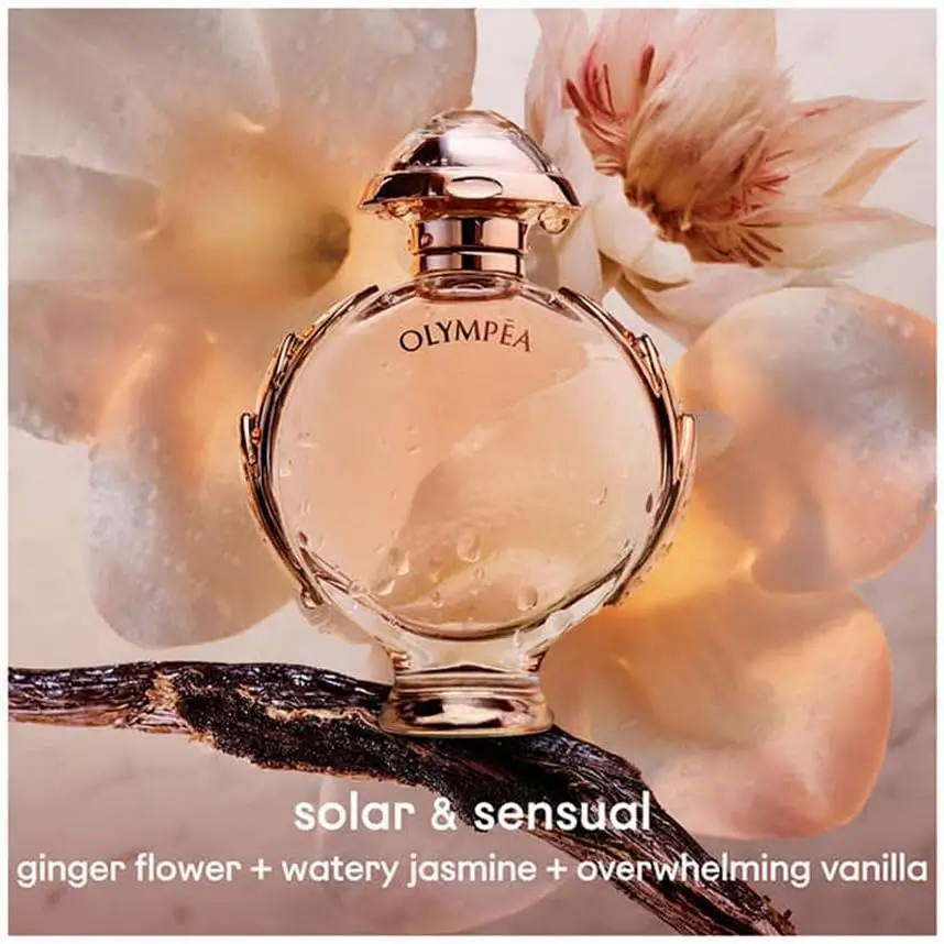 frasco do perfume Olympea EDP sobre galho, cercado por flores em tom pêssego; estética solar e sensual com notas de flor de gengibre, jasmim aquático e baunilha
